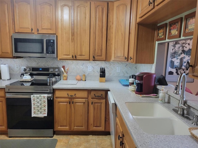 kitchen with backsplash, light stone countertops, sink, and appliances with stainless steel finishes