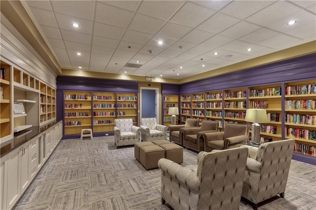 carpeted cinema featuring a drop ceiling and built in shelves