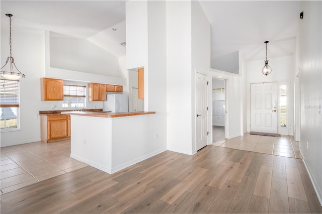 kitchen featuring kitchen peninsula, white refrigerator, decorative light fixtures, and light hardwood / wood-style flooring