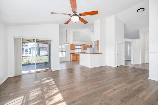 unfurnished living room with wood-type flooring, high vaulted ceiling, and ceiling fan