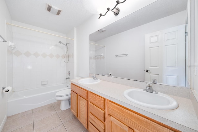 full bathroom featuring vanity, tile patterned floors, tiled shower / bath combo, toilet, and a textured ceiling