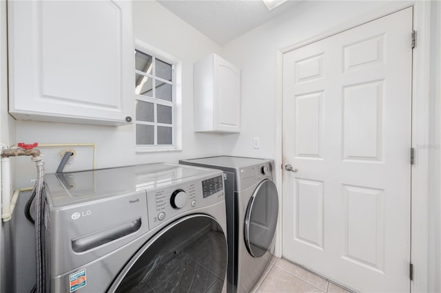 laundry area featuring washer and dryer, light tile patterned floors, a textured ceiling, and cabinets