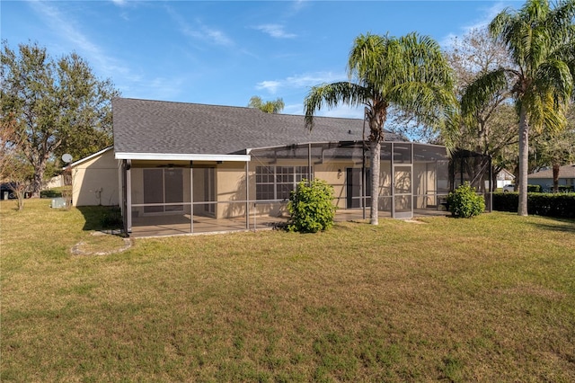 back of property with a lawn and glass enclosure