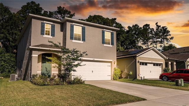 view of front of property with a yard, a garage, and central air condition unit