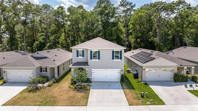 front of property with solar panels, a garage, and a front lawn