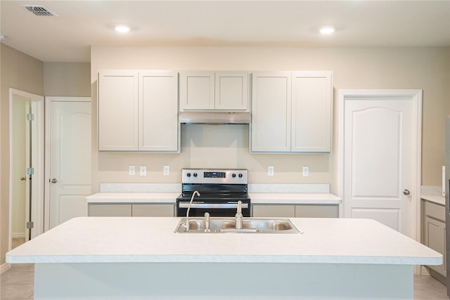 kitchen with light tile patterned floors, electric range, a center island with sink, and sink