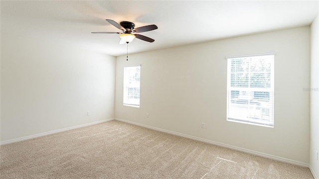 carpeted spare room featuring ceiling fan and a healthy amount of sunlight