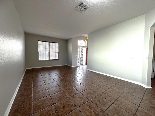 unfurnished room with a textured ceiling and dark tile patterned floors