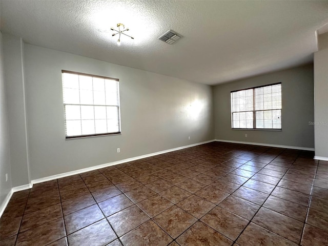 unfurnished room featuring dark tile patterned floors and a textured ceiling