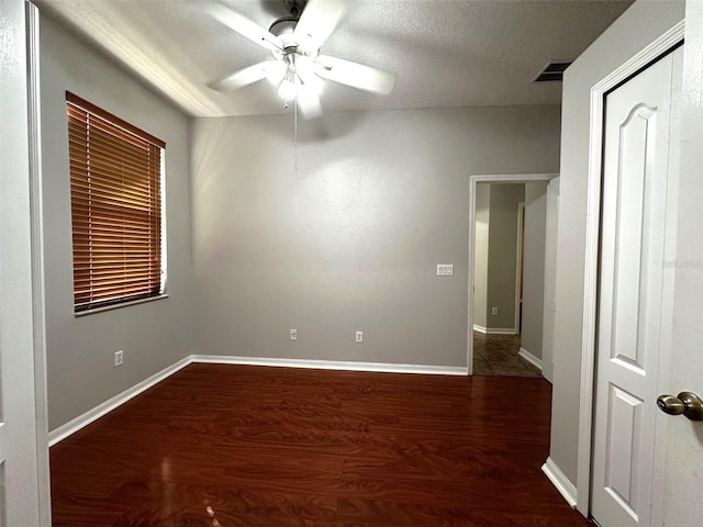 empty room featuring a textured ceiling, ceiling fan, and dark hardwood / wood-style floors