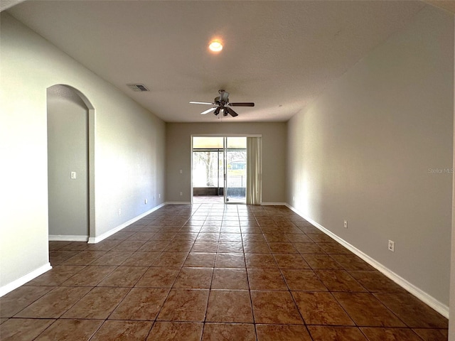 spare room with ceiling fan and dark tile patterned floors