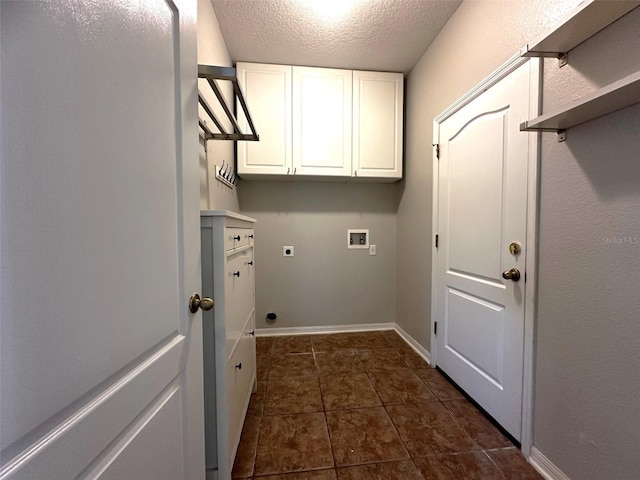 laundry area with cabinets, hookup for a washing machine, a textured ceiling, electric dryer hookup, and dark tile patterned flooring