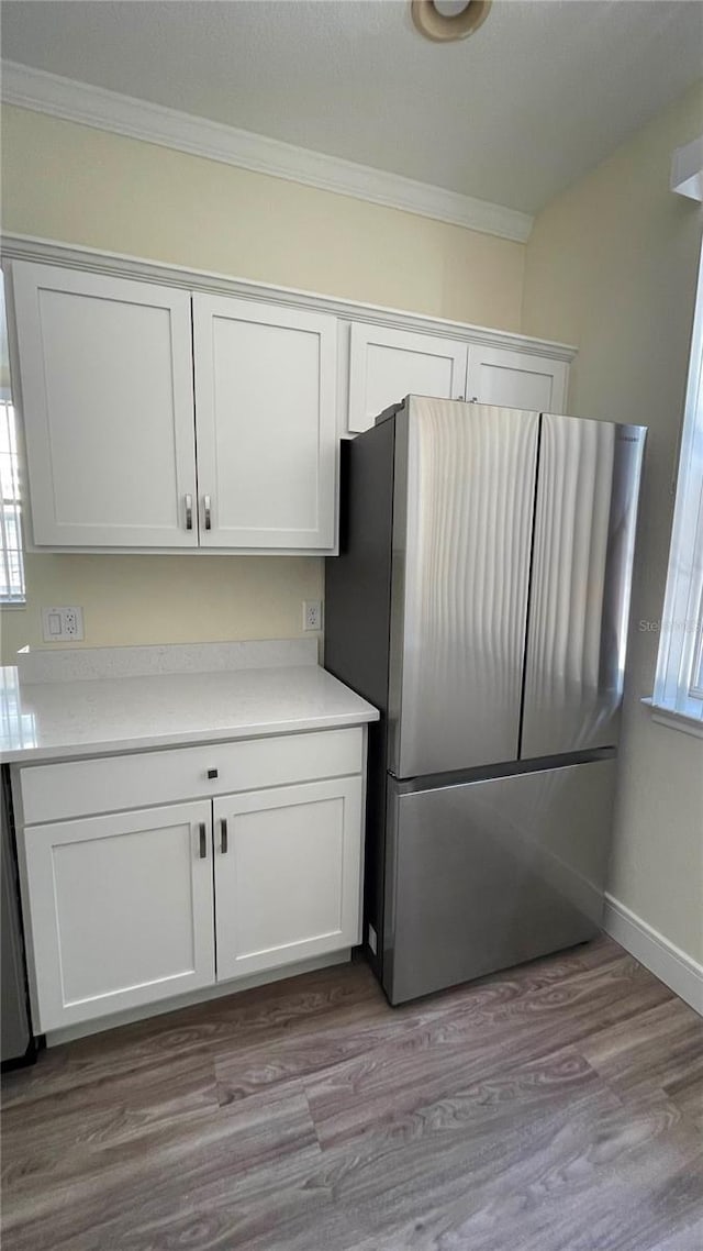 kitchen with stainless steel fridge, light wood-type flooring, and white cabinetry