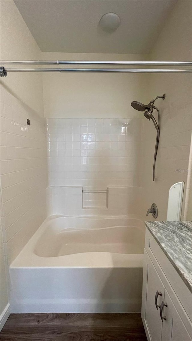 bathroom featuring washtub / shower combination, wood-type flooring, and vanity