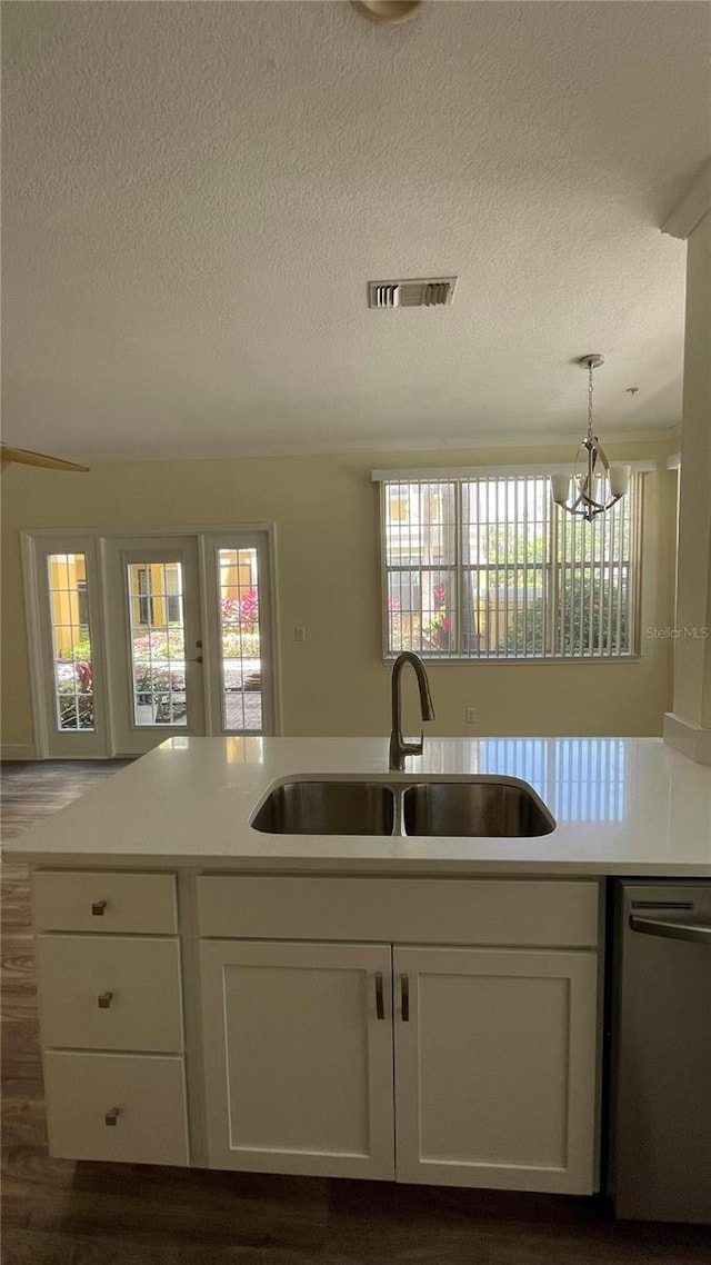 kitchen with dishwasher, sink, hanging light fixtures, a chandelier, and white cabinets