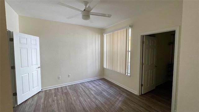 empty room with ceiling fan and dark hardwood / wood-style flooring