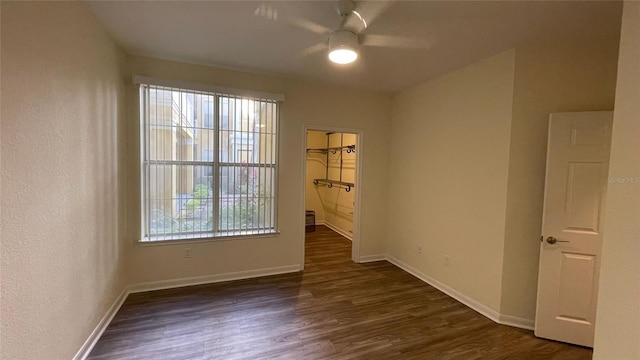 spare room featuring a wealth of natural light, ceiling fan, and dark wood-type flooring