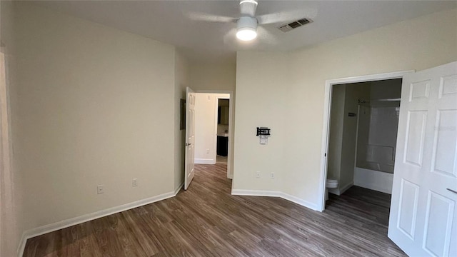 unfurnished bedroom featuring connected bathroom, dark hardwood / wood-style floors, and ceiling fan