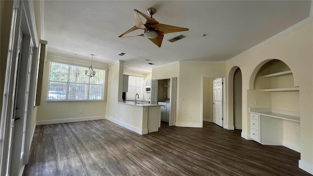 unfurnished living room with ornamental molding, ceiling fan with notable chandelier, dark wood-type flooring, sink, and built in features