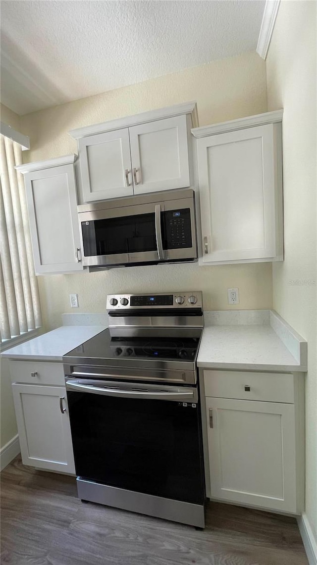 kitchen with white cabinets, wood-type flooring, a textured ceiling, and appliances with stainless steel finishes