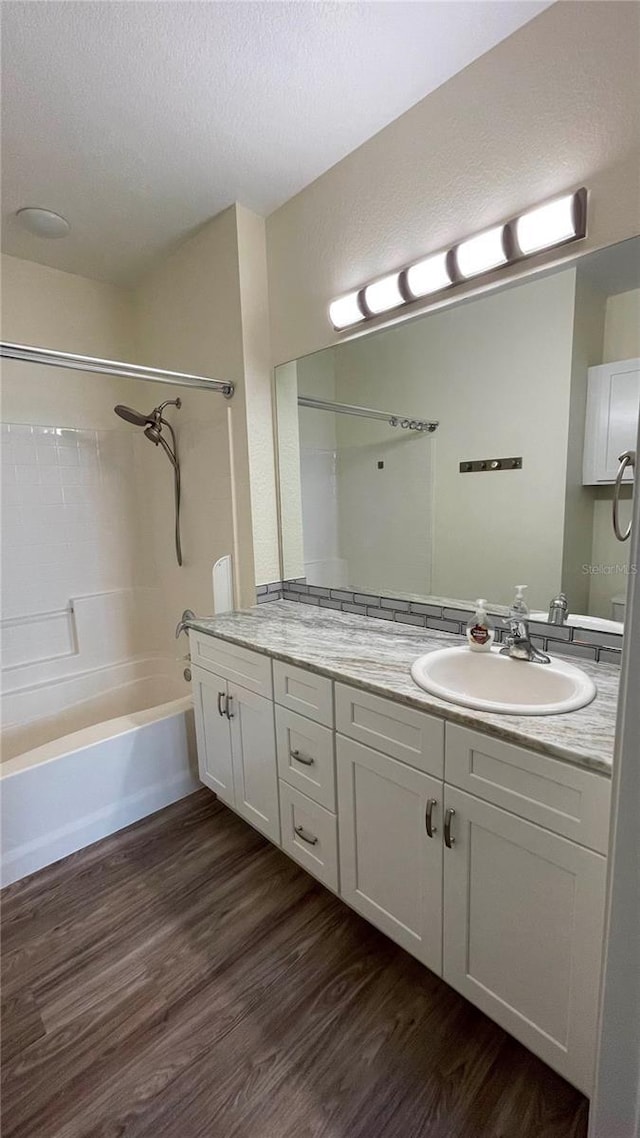 bathroom featuring vanity, washtub / shower combination, a textured ceiling, and hardwood / wood-style flooring