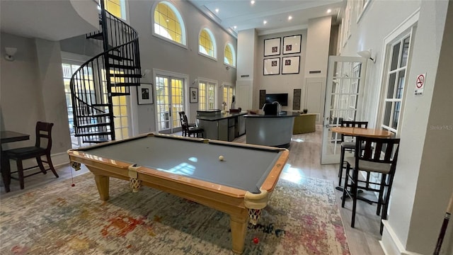 game room with light hardwood / wood-style flooring, a towering ceiling, and pool table