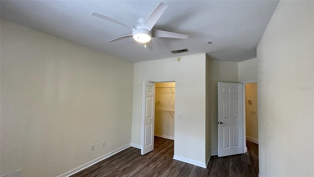 unfurnished bedroom featuring dark wood-type flooring, ceiling fan, a closet, and a spacious closet