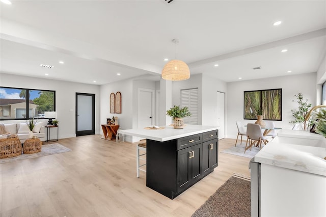 kitchen featuring decorative light fixtures, a center island, light wood-type flooring, and a breakfast bar