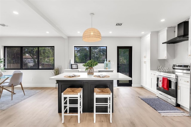 kitchen with a kitchen breakfast bar, wall chimney exhaust hood, decorative light fixtures, white cabinets, and stainless steel range with electric cooktop