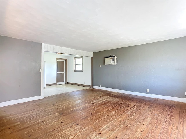 spare room featuring wood-type flooring and an AC wall unit