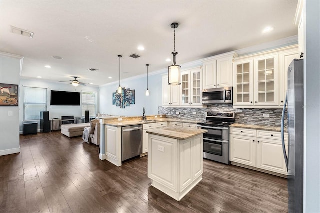 kitchen featuring sink, light stone countertops, appliances with stainless steel finishes, decorative light fixtures, and kitchen peninsula