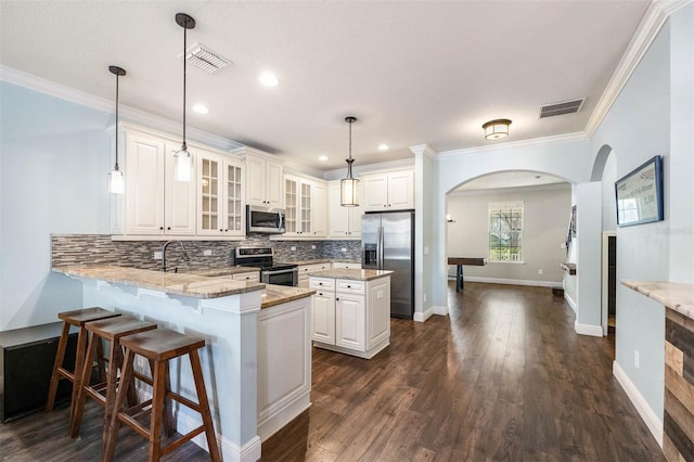 kitchen featuring kitchen peninsula, appliances with stainless steel finishes, light stone countertops, decorative light fixtures, and a center island