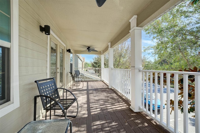 wooden deck featuring covered porch and ceiling fan