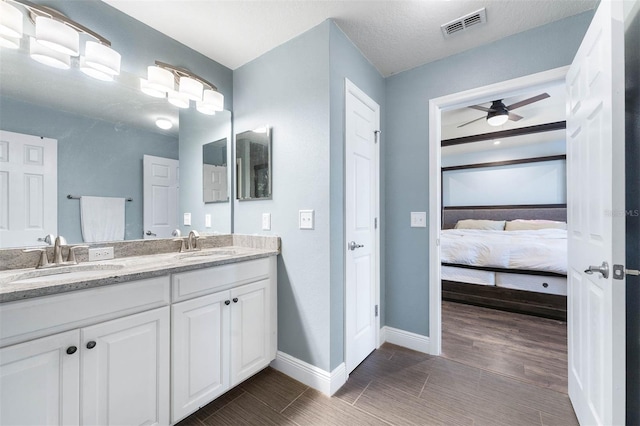 bathroom with ceiling fan, a textured ceiling, and vanity