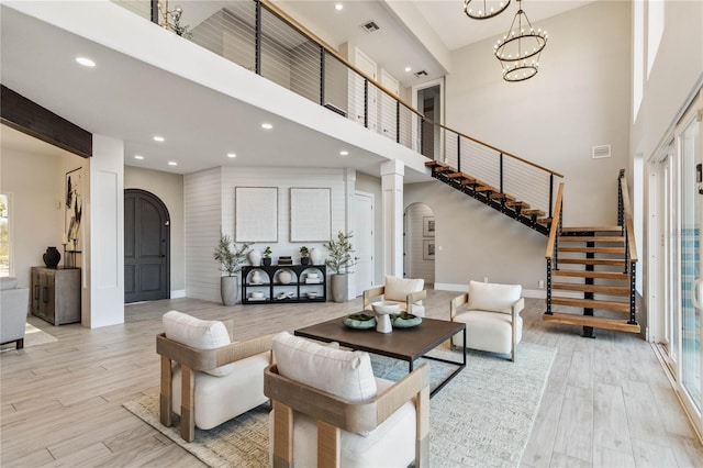 living room with light hardwood / wood-style floors, a high ceiling, and a chandelier