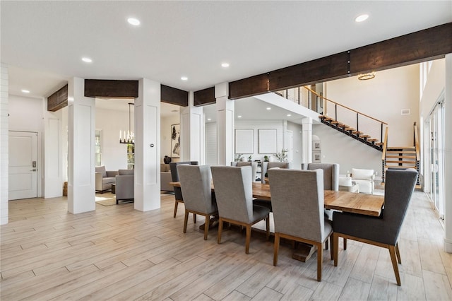 dining area featuring an inviting chandelier, light hardwood / wood-style flooring, decorative columns, and beam ceiling