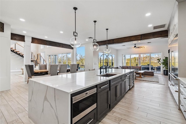 kitchen featuring white cabinets, beamed ceiling, a large island, and pendant lighting