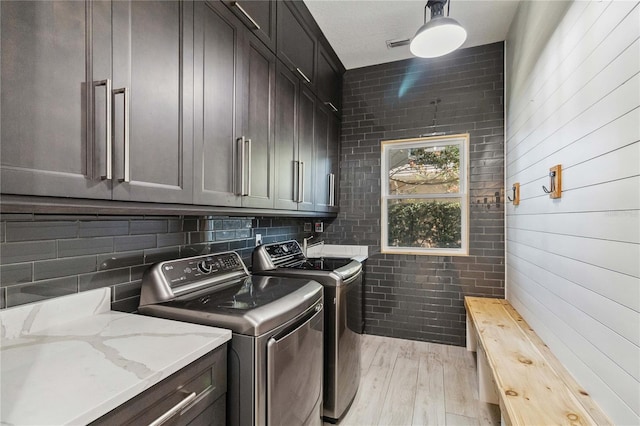 washroom featuring washing machine and dryer, light hardwood / wood-style flooring, and cabinets