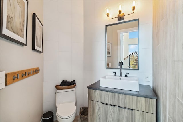 bathroom with toilet, tile walls, and vanity