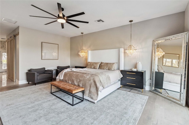 bedroom with hardwood / wood-style flooring, ceiling fan, and a barn door