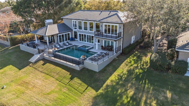 rear view of property featuring a patio, a yard, a swimming pool with hot tub, a balcony, and an outdoor hangout area