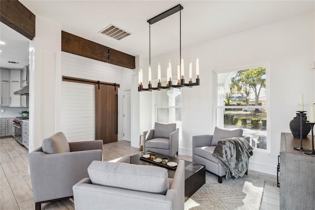 living room featuring beam ceiling, a barn door, and light wood-type flooring