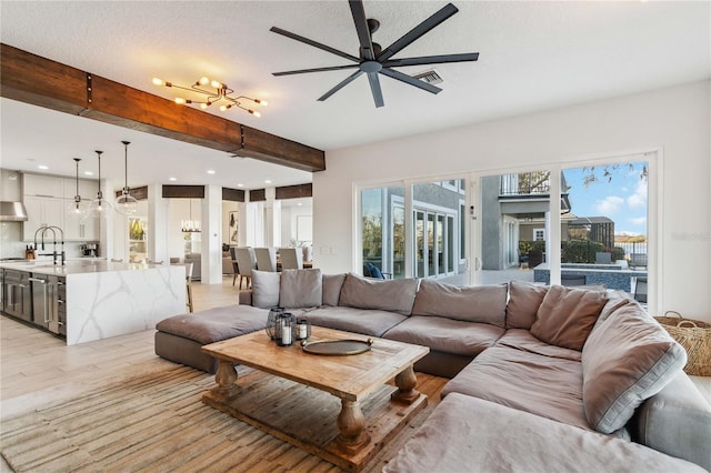 living room featuring sink, light hardwood / wood-style flooring, ceiling fan, and beam ceiling