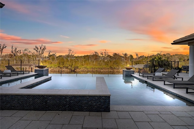 pool at dusk with a patio area