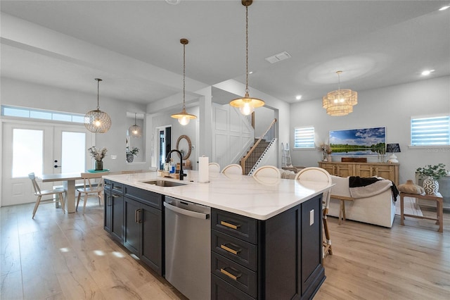 kitchen featuring stainless steel dishwasher, a healthy amount of sunlight, sink, pendant lighting, and an island with sink