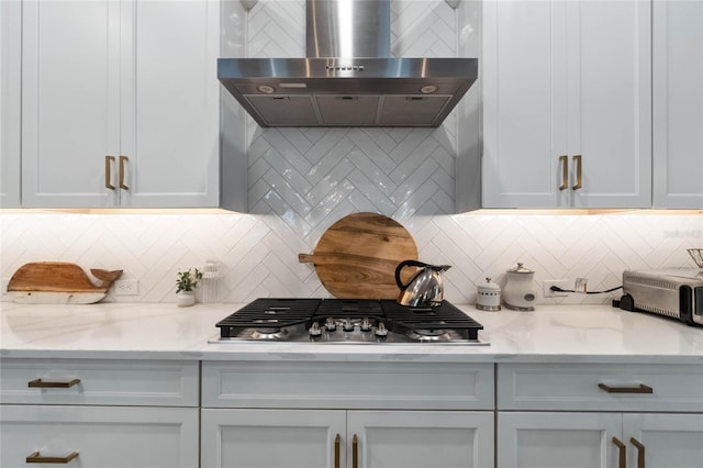 kitchen with light stone counters, wall chimney range hood, and tasteful backsplash