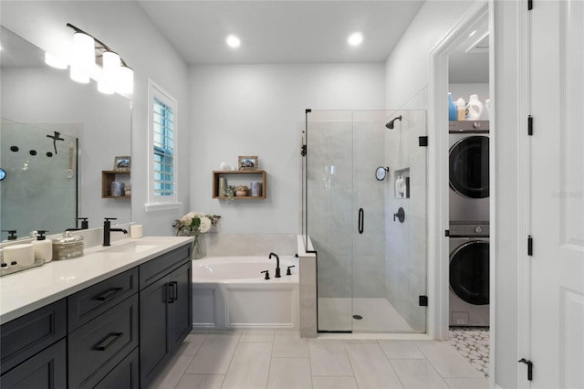 bathroom featuring tile patterned flooring, vanity, stacked washing maching and dryer, and independent shower and bath