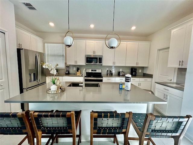 kitchen with white cabinets, appliances with stainless steel finishes, decorative light fixtures, and sink