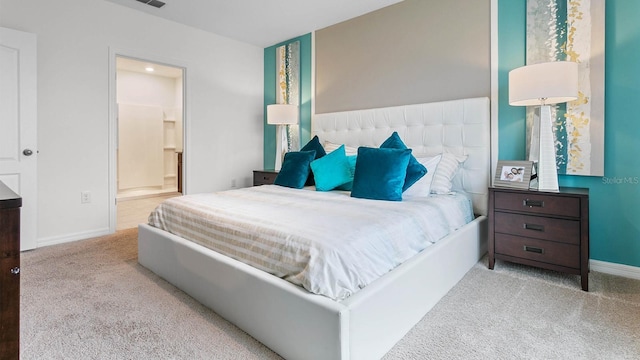 bedroom featuring connected bathroom and light colored carpet