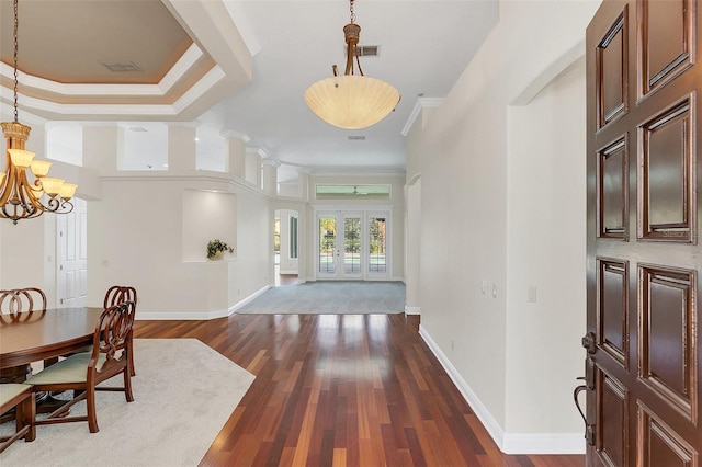 foyer featuring a towering ceiling, an inviting chandelier, dark wood-type flooring, and ornamental molding